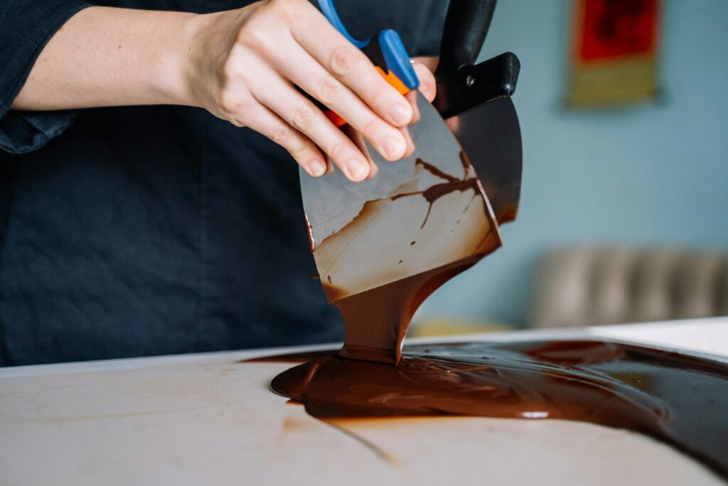 Close-up of chocolate being tempered by hand, showcasing the process of food preparation.